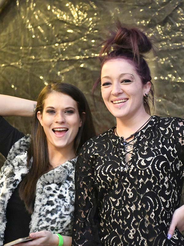 Woman with piercings smiling with another tattooed girl looking happy