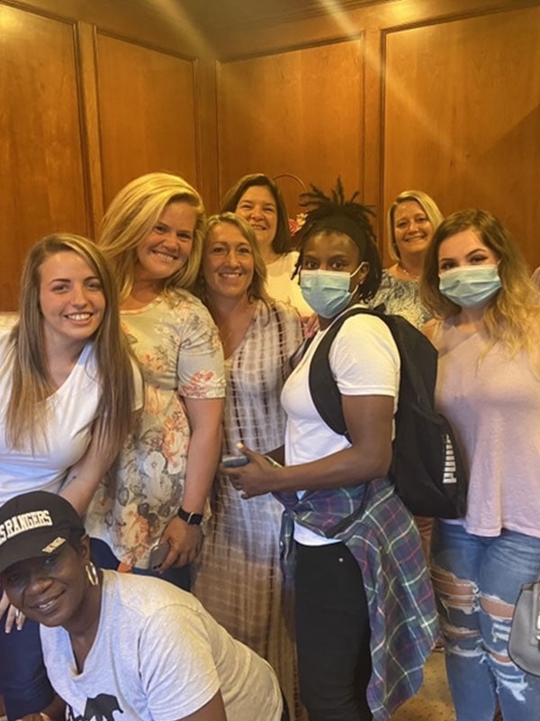 Photo of Multiple Girls Some Wearing Masks and smiling in an empty hall