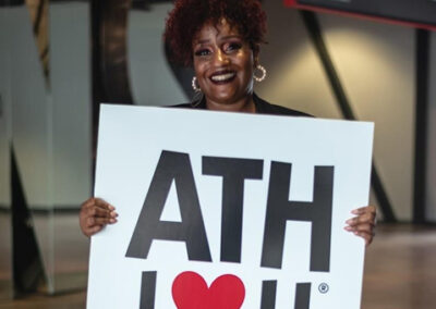 Portrait of an African-American Lady holding up a sign saying "ATH I love you"