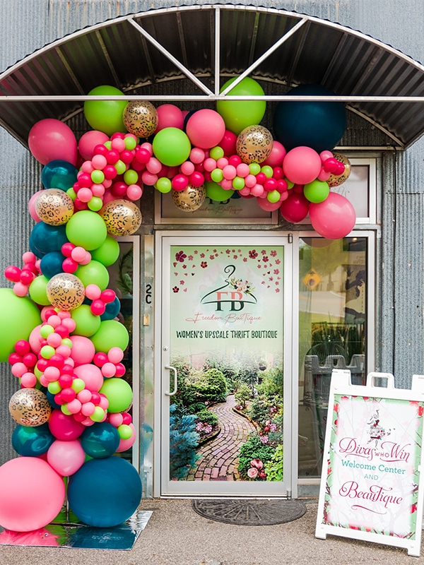 Photo of Building Representing Freedom Boutique with Colorful Balloons and poster with Divas Who Win Branding