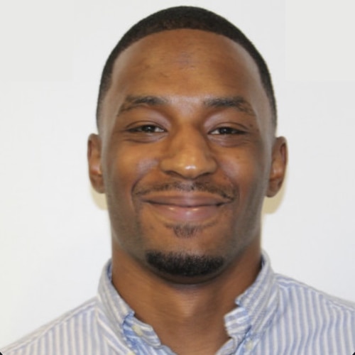 Potrait of a Smiling Africa-American Guy wearing a shirt with a grey backdrop. Cedryc