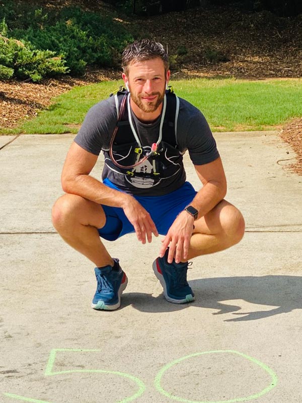 Portrait of Middle Aged Athlete Squatting in front of a Number 50 written on the concrete with chalk for Divas Who Win