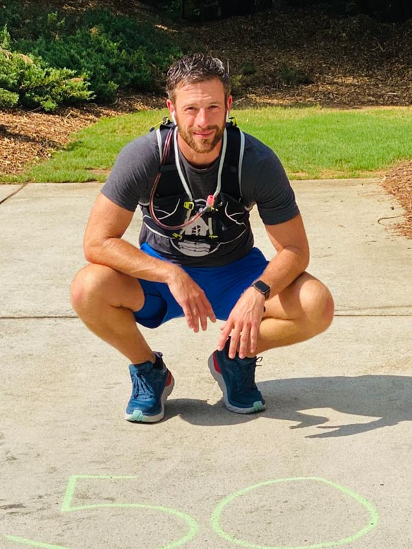 addiction-recovery-and-non-profit-divas-who-win-athens-GA-freedom-run-ryan Portrait of Middle Aged Athlete Squatting in front of a Number 50 written on the concrete with chalk for Divas Who Win