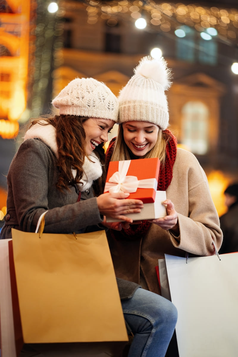 Happy women friends exchanging christmas present.